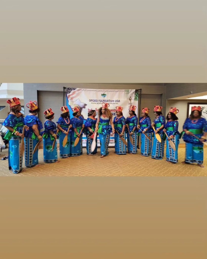Women of OFUSA in blue sequined attire with green sashes and traditional headpieces