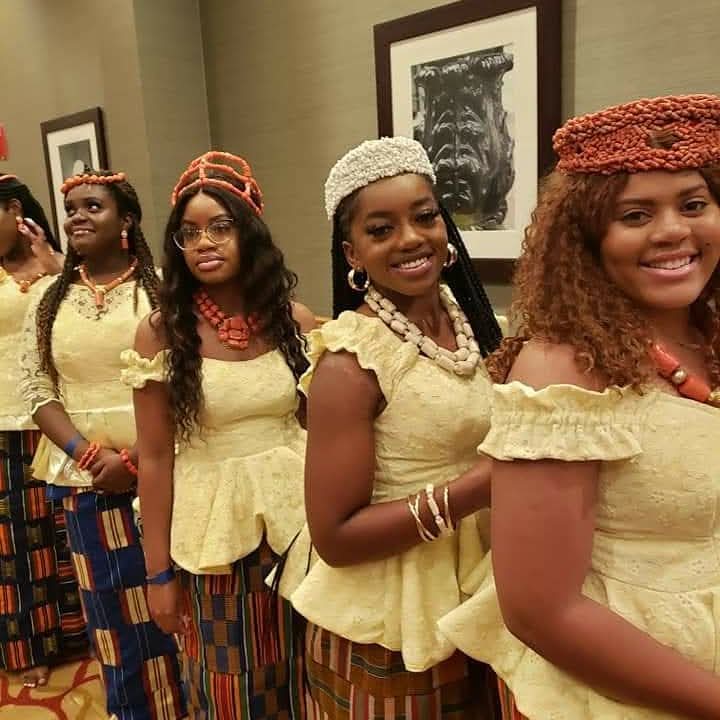 Women holding traditional paddles in coordinated convention attire